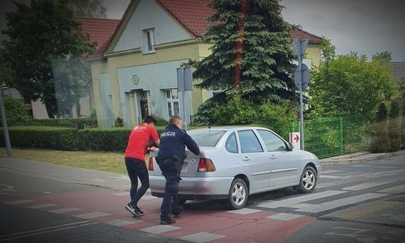 policjant i mężczyzna pchają samochód