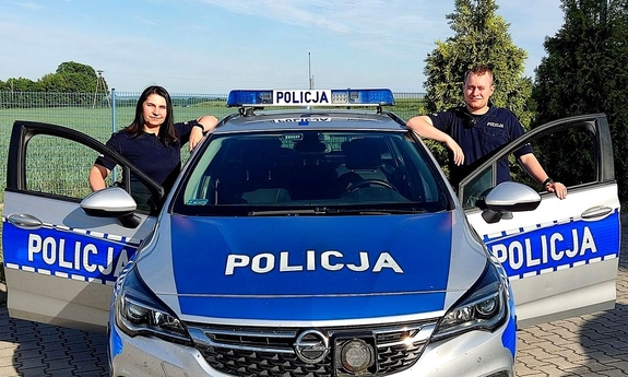 policjant i policjantka przy radiowozie