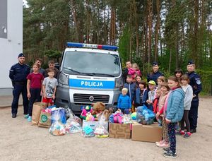 policjantki i policjant z dziećmi przy radiowozie i zebrane dary