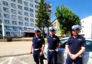 Trzej umundurowani policjanci stojący obok siebie na tle budynku Komendy Miejskiej Policji w Białymstoku