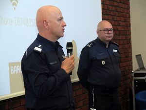 Komendant Główny Policji mówiący do mikrofonu, w tle drugi policjant w mundurze