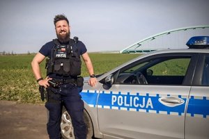 policjant stoi przy radiowozie