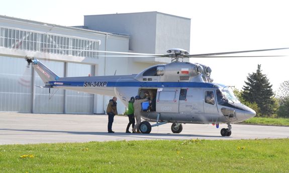 Policyjny śmigłowiec W-3 Sokół oraz policyjny lotnik, który pomaga wysiąść lekarzom ze śmigłowca