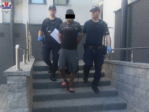 dwaj policjanci prowadzą zatrzymanego po schodach