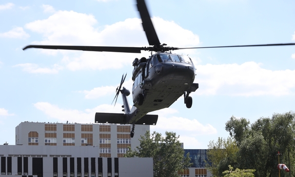 Black Hawk podczas startu, w tle budynki kompleksu szpitalnego oraz urządzenie wskazujące siłę wiatru.