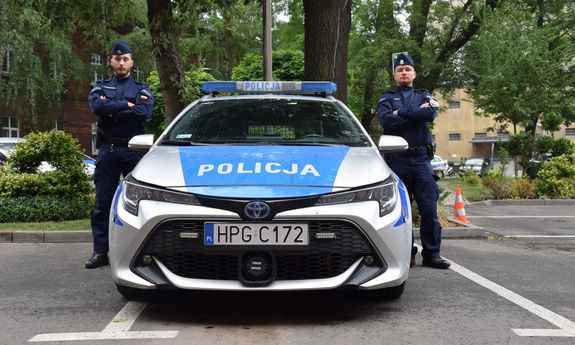 dwaj policjanci stojący przy radiowozie