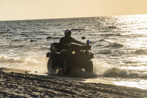 Policjant na quadzie patrolujący morską plażę.