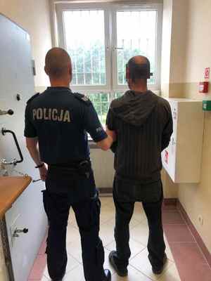 umundurowany policjant z zatrzymanym mężczyzną