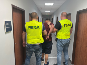 dwaj policjanci prowadzą zatrzymanego mężczyznę
