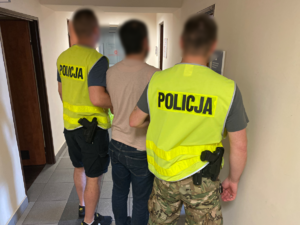 dwaj policjanci prowadzą zatrzymanego mężczyznę