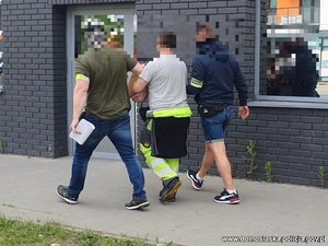 dwaj policjanci prowadzą zatrzymanego mężczyznę