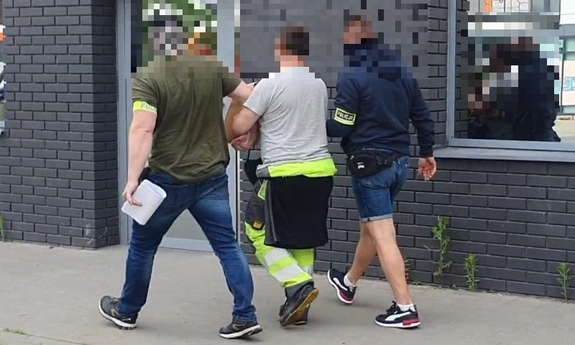 dwaj policjanci prowadzą zatrzymanego mężczyznę