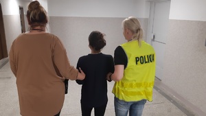 dwie policjantki po cywilnemu prowadza korytarzem zatrzymana kobietę