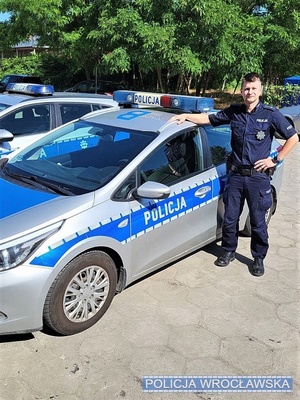 policjant stoi przy radiowozie