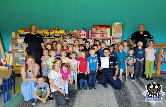 Policjanci z grupą dzieci pozują do zdjęcia w szkole.