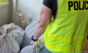 Policjant stoi obok worków z krajanką tytoniową
