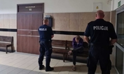 dwóch policjantów stoi naprzeciwko zatrzymanego mężczyzny w sądzie
