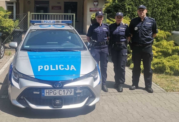 troje policjantów stojących przy radiowozie