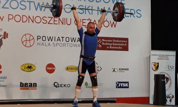 funkcjonariusz w stroju sportowym podnosi sztangę do góry