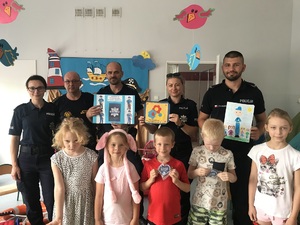 Policjanci i strażnik miejski pozują do zdjęcia z grupą dzieci.