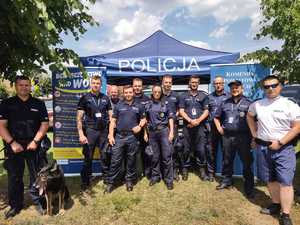 Grupa policjantów pozuje do zdjęcia przy namiocie profilaktycznym.