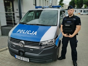 policjant stoi przy radiowozie