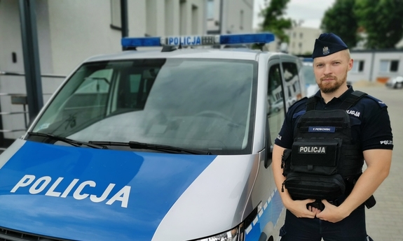 policjant stoi przy radiowozie