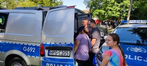 Policjant pokazuje uczestnikom imprezy wnętrze furgonetki policyjnej.