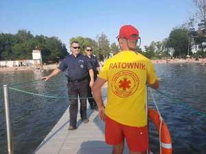 Dwaj policjanci i ratownik wodny stojący na pomoście.