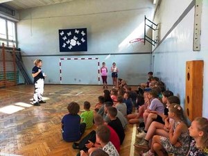 W sali gimnastycznej policjantka rozmawia z dziećmi.