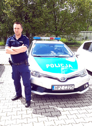 policjant stoi przy radiowozie