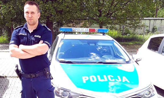 policjant stoi przy radiowozie