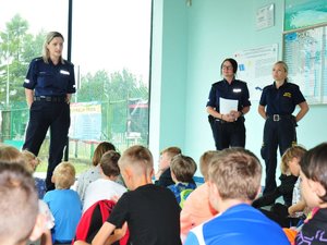 Policjantki i strażniczka miejska rozmawiają z grupą dzieci.