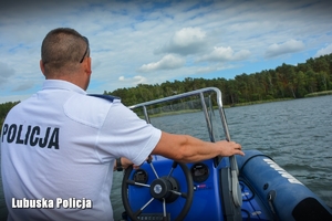 Policjant steruje motorówką po akwenie wodnym.