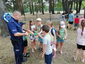 Policjant rozdaje odblaski dzieciom.