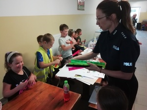 Policjantka rozdaje dzieciom odblaski.