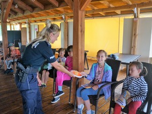 Policjantka rozdaje dzieciom gadżety promujące akcję &quot;Kręci mnie bezpieczeństwo nad wodą&quot;.