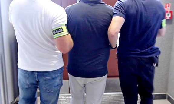 policjanci prowadzą zatrzymanego mężczyznę