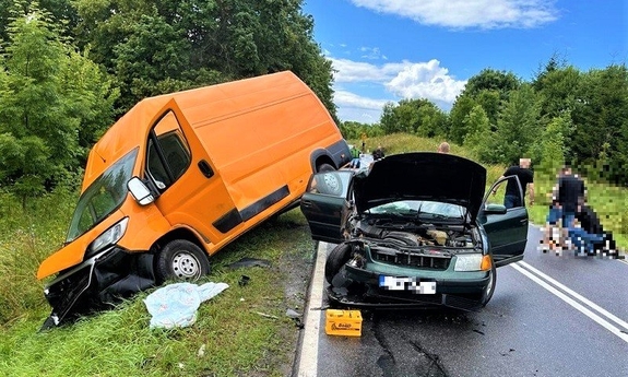 miejsce wypadku drogowego, na drodze stoi rozbity samochód osobowy, w rowie samochód typu bus