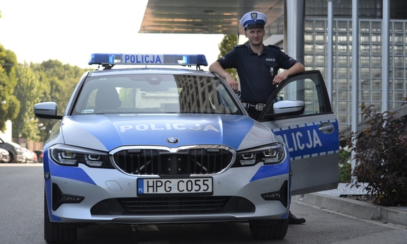 policjant stoi przy radiowozie