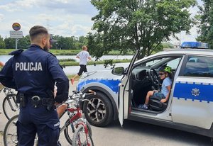 policjant z rowerem stoi obok radiowozu