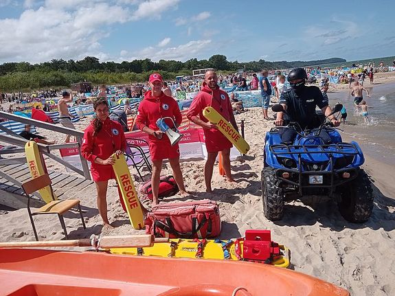 policjant na quadzie na plaży z ratownikami