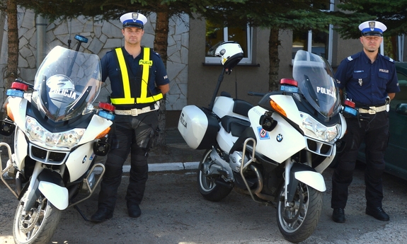 dwaj policjanci stoją przy motocyklach