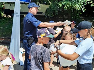policjant rozdaje dzieciom ulotki profilaktyczne