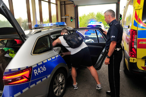 na zdjęciu mężczyzna pakuje do środka radiowozu pojemnik z sercem, obok przy radiowozie stoi umundurowany policjant