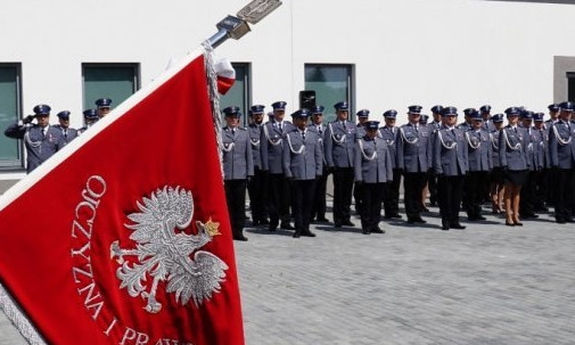 Sztandar z godłem Polski i policjanci w tle