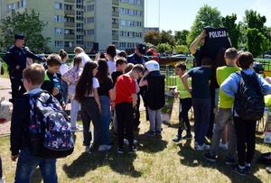 Policjanci prezentują swoje umundurowanie grupie dzieci.