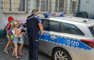 Policjant pokazuje dzieciom radiowóz.