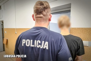 policjant z zatrzymanym przed drzwiami aresztu