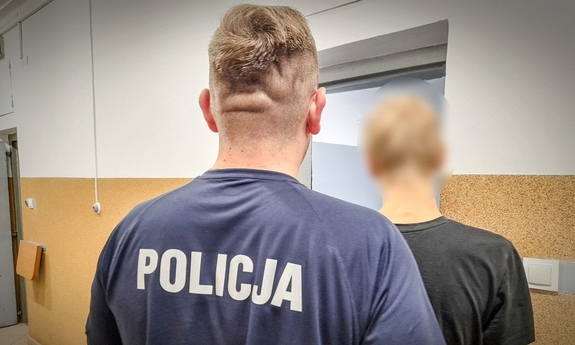 policjant z zatrzymanym przed drzwiami aresztu